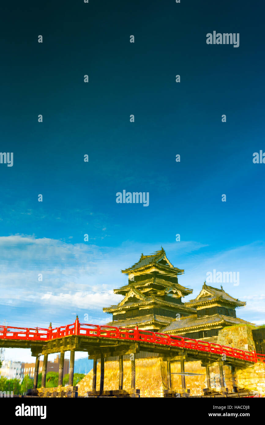 A painterly mirror image of Matsumoto Castle upside down seen as water reflection on a blue sky day in Nagano Prefecture, Japan. Stock Photo