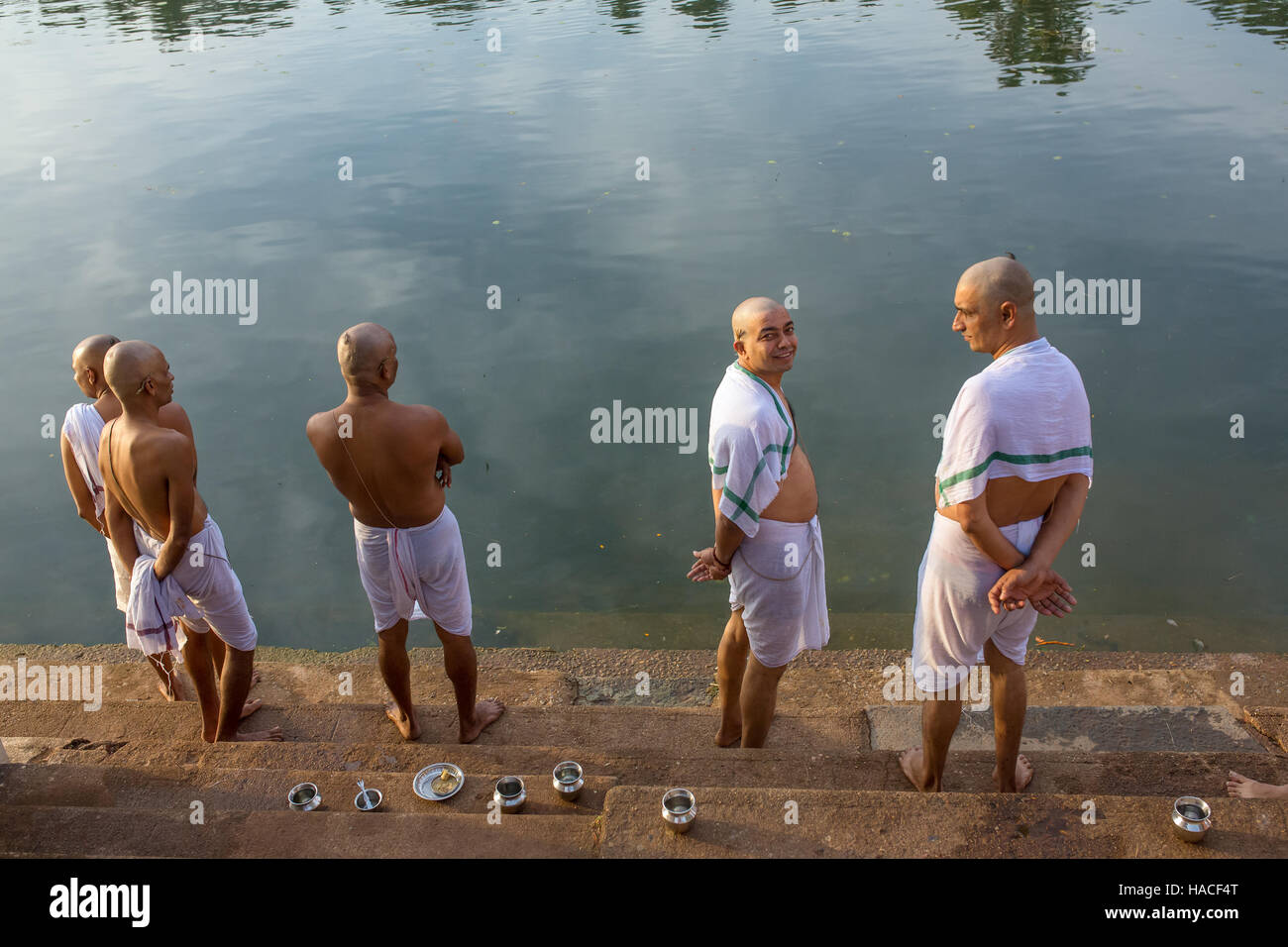 Unidentified hindu piligrims standing on the bank of the sacred lake in Gokarna. The city is a holy pilgrimage site Stock Photo