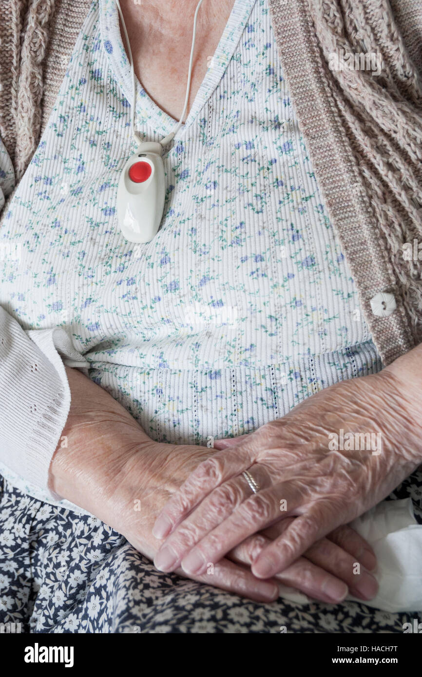 Elderly woman in her own home wearing care assistance alarm which is linked to an emergency response service. England. UK Stock Photo