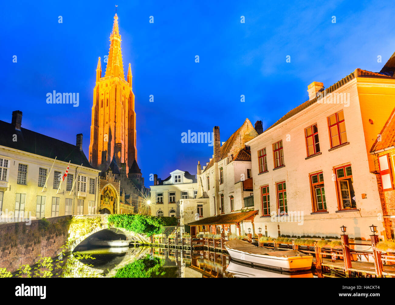 Bruges, Belgium. Church of Our Lady, Vrouwekerk. Night shot of historic medieval buildings along a canal in Brugge, Flanders. Stock Photo