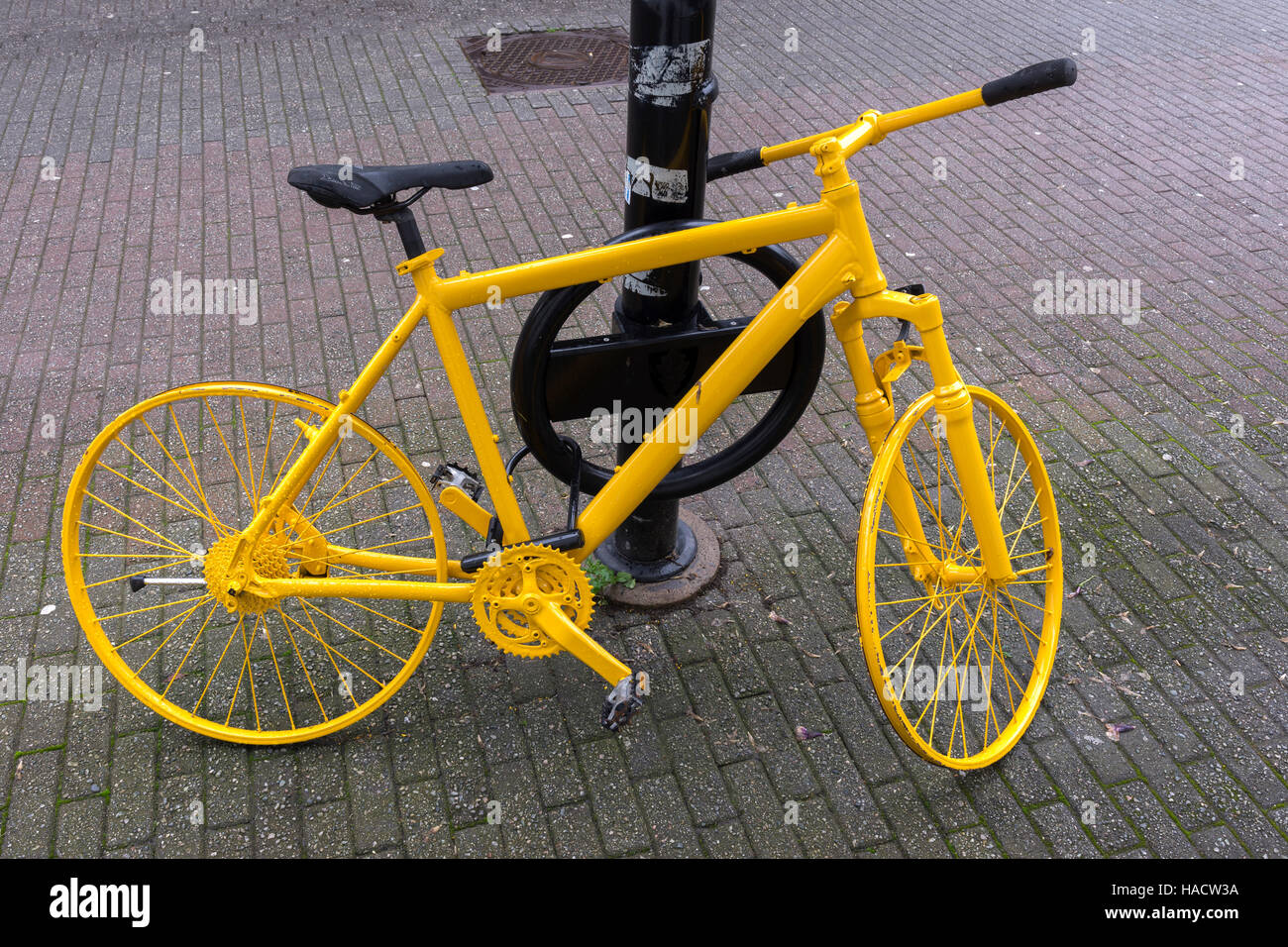 yellow bicycle tied to a pole in Egersund in Norway Stock Photo