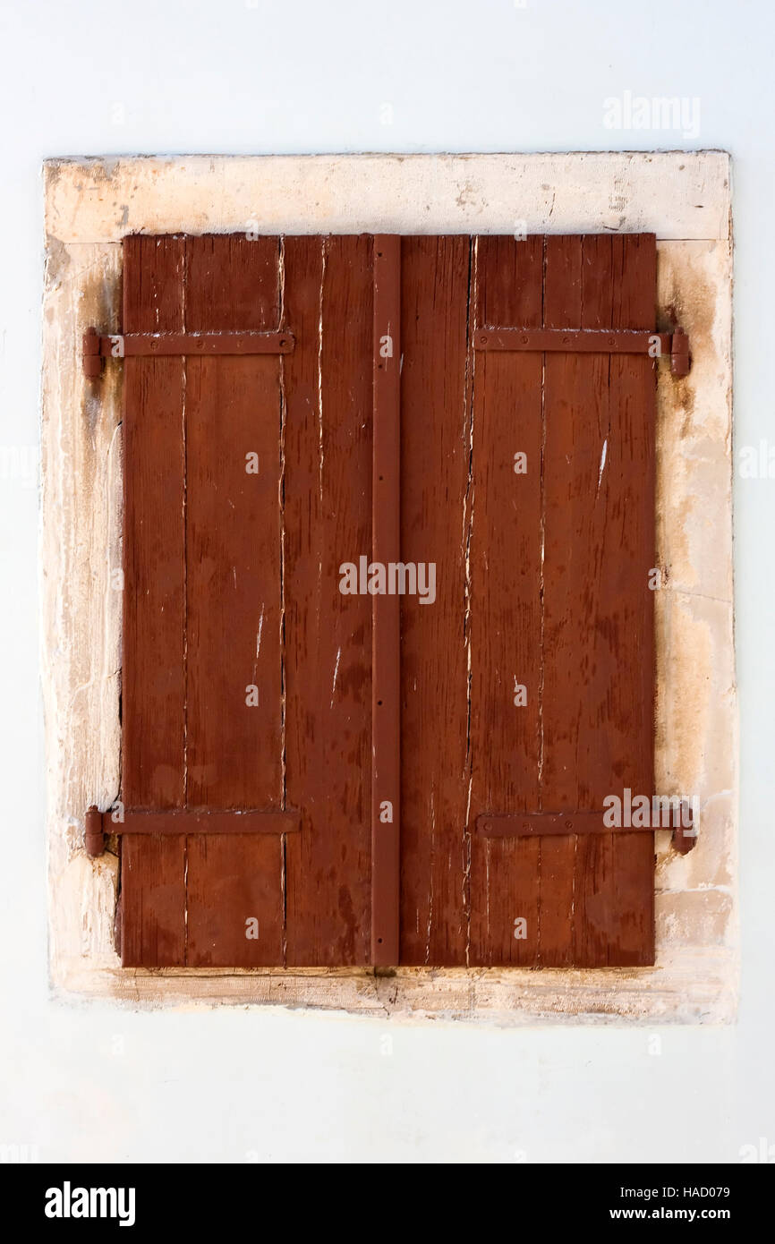 Window with closed brown shutters on old house in Croatia Stock Photo