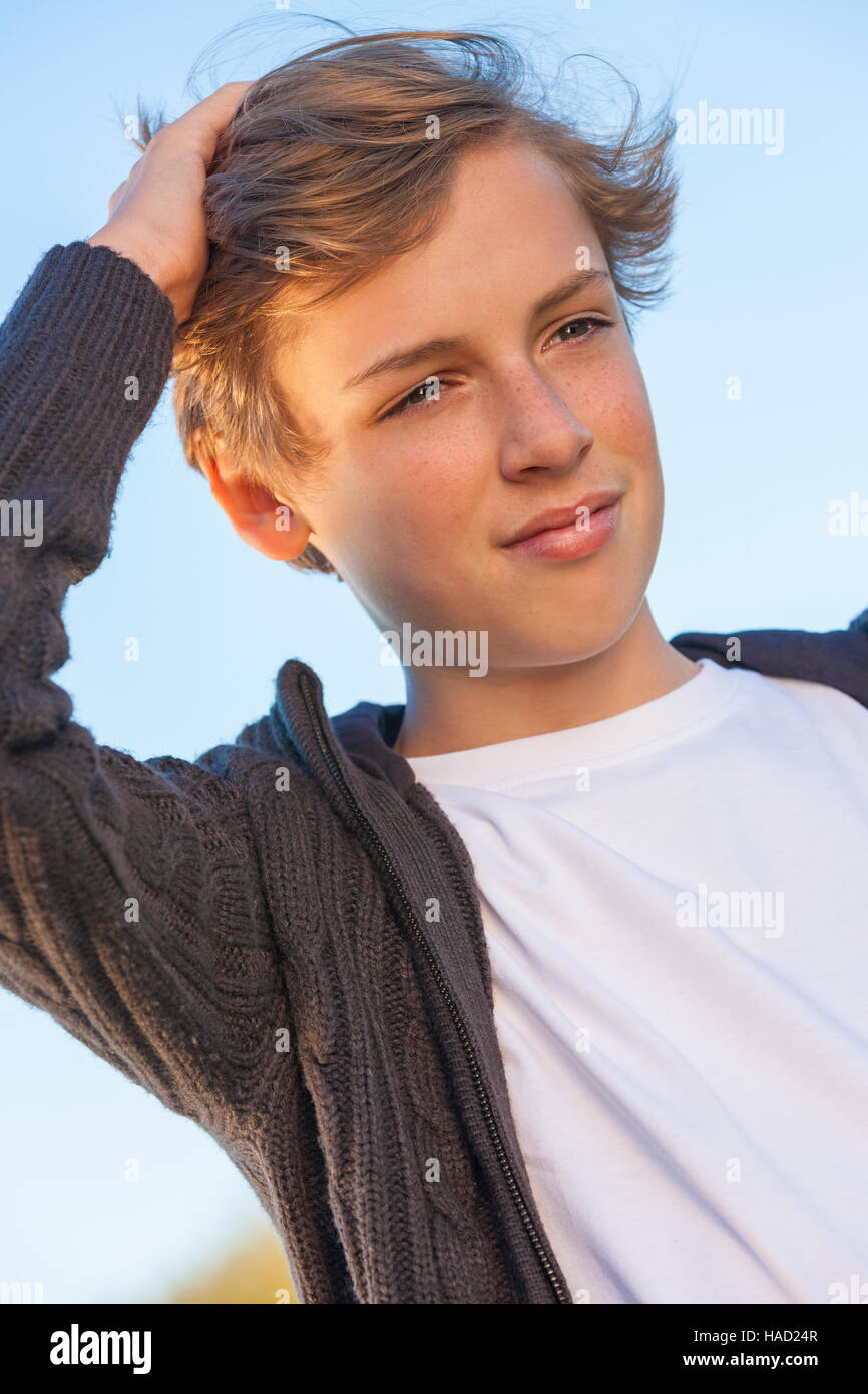 Young happy laughing male boy teenager blond child outside in summer sunshine wearing white t-shirt Stock Photo