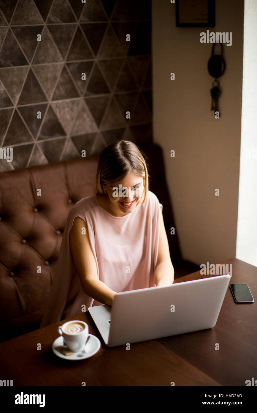 Young woman with laptop sitting in cafe Stock Photo - Alamy