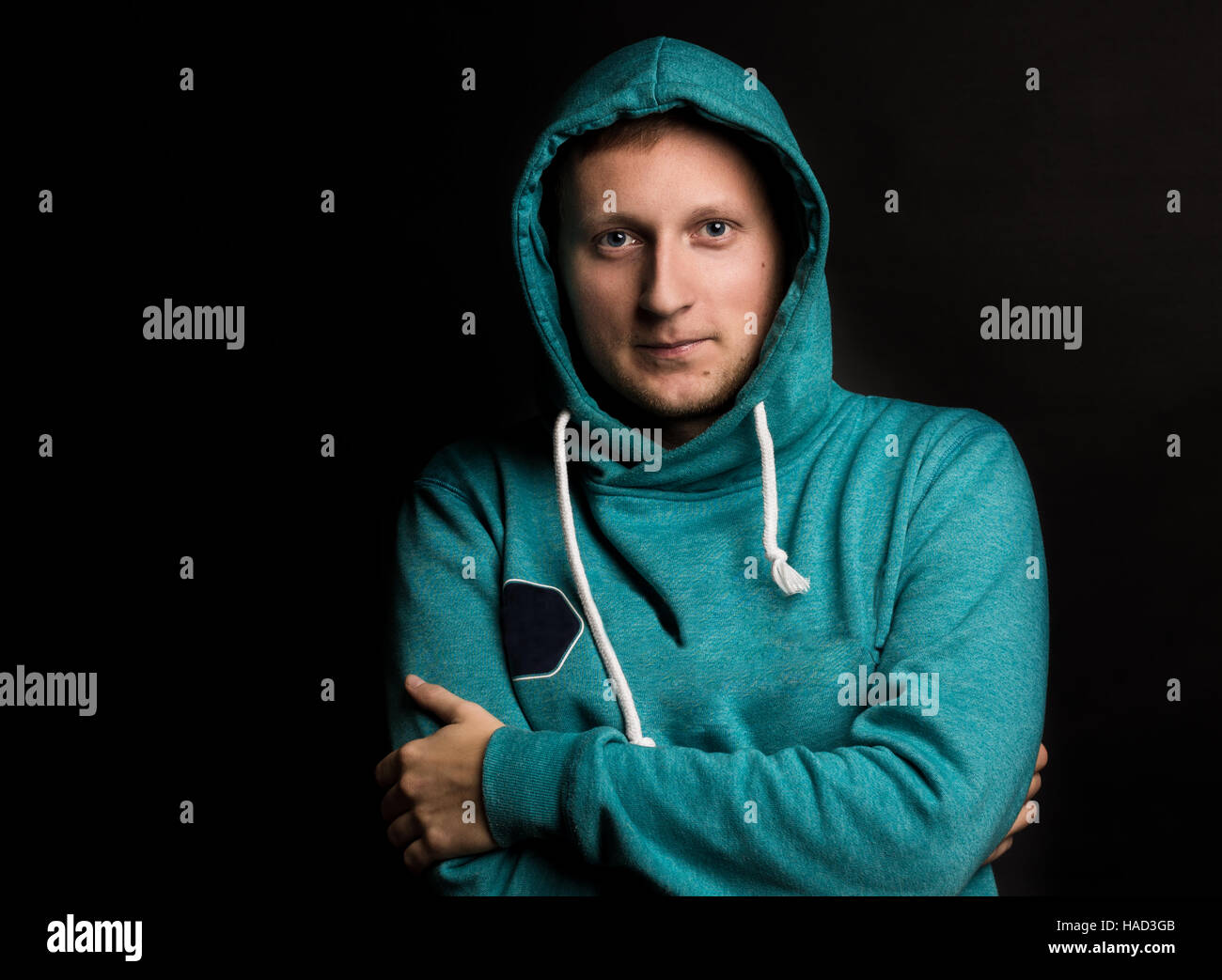 caucasian man dressed in a blue jacket with a hood looking at the screen. Black background Stock Photo