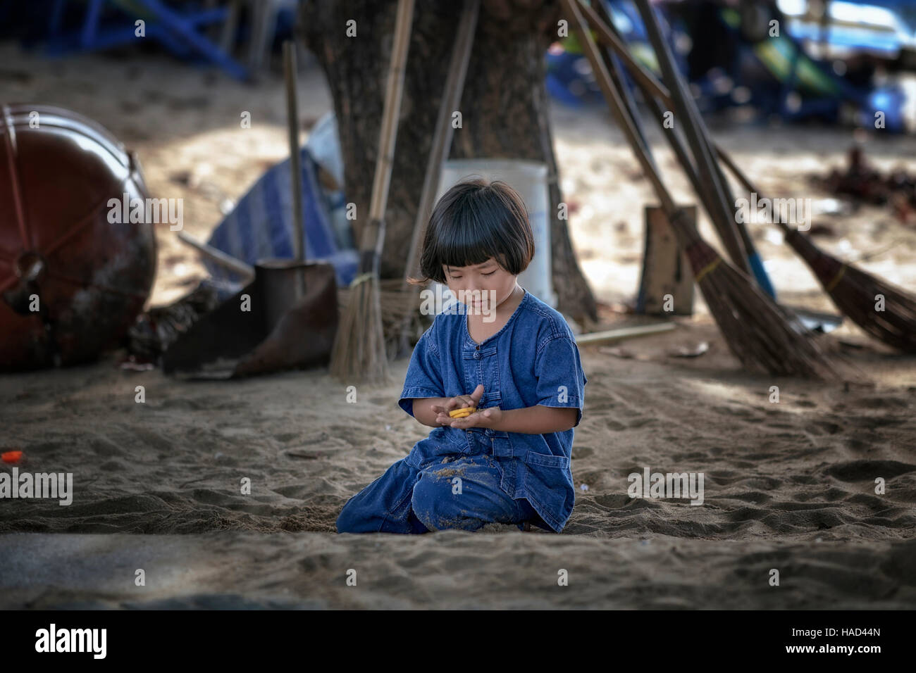 Child playing alone outside. Cute young Thai girl happy and content to play alone in the sand. Pattaya Thailand S. E. Asia Stock Photo