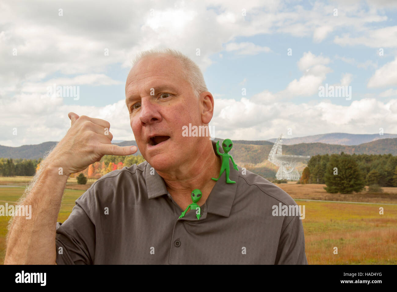 Man making call me gestures with plastic aliens in fron to the Green Bank Telescope. Stock Photo
