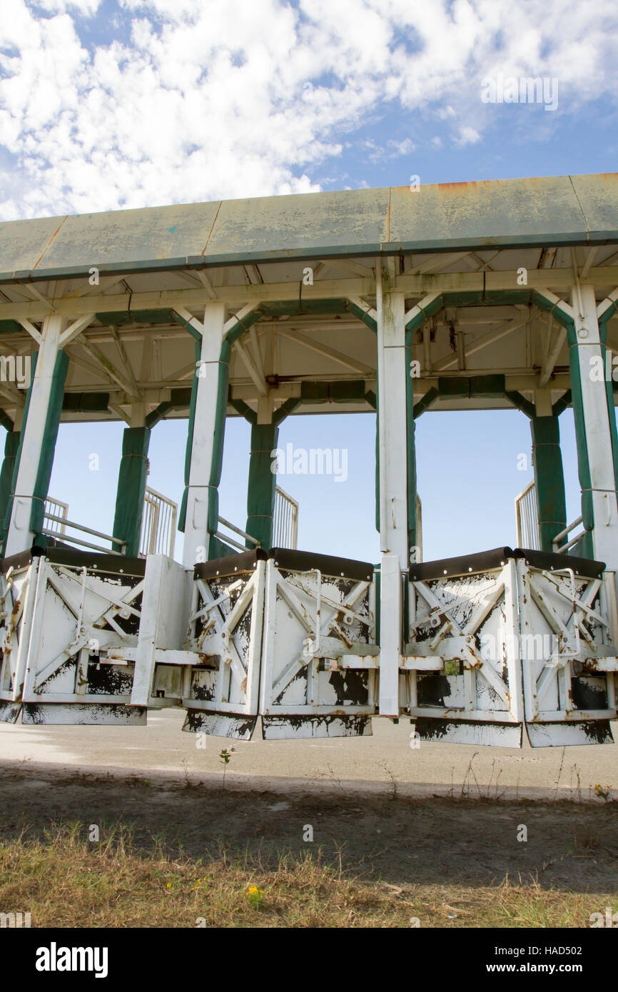 Empty horse racing starting gate rusting in field against blue skies. Stock Photo