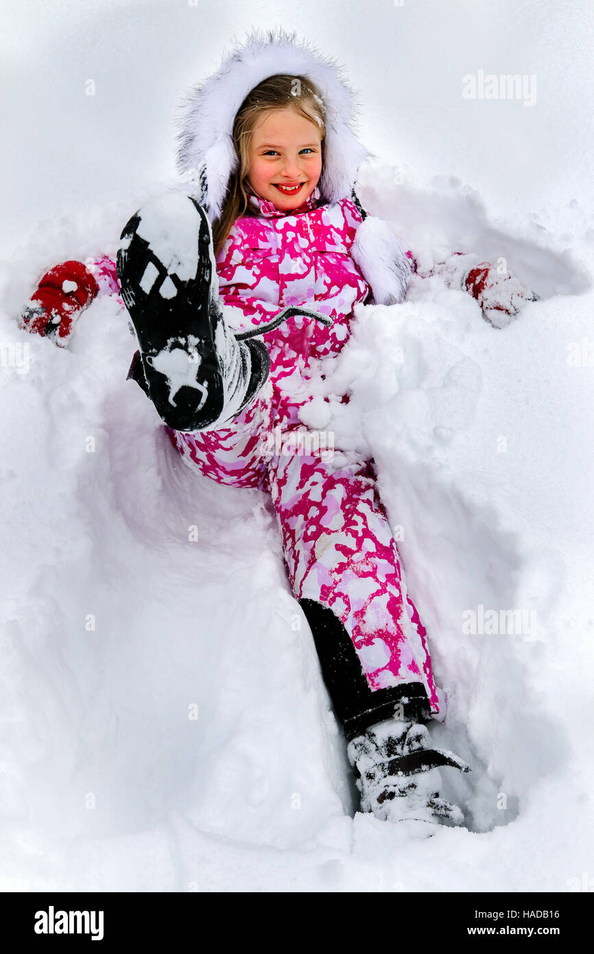 Little girl wearing winter clothes lying in deep snow Stock Photo - Alamy