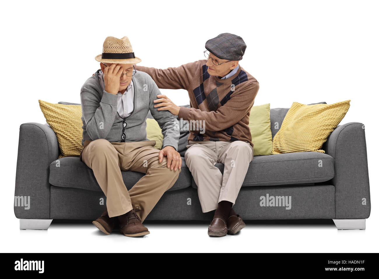 Elderly man sitting on a sofa and comforting another man isolated on white background Stock Photo