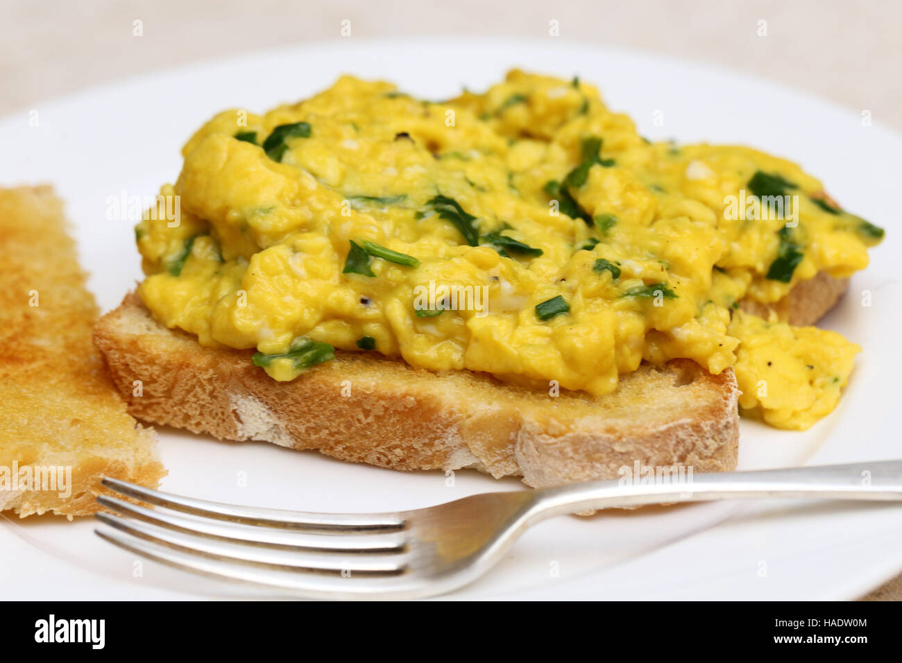 A light meal of scrambled egg cooked with baby spinach leaves served on toast Stock Photo