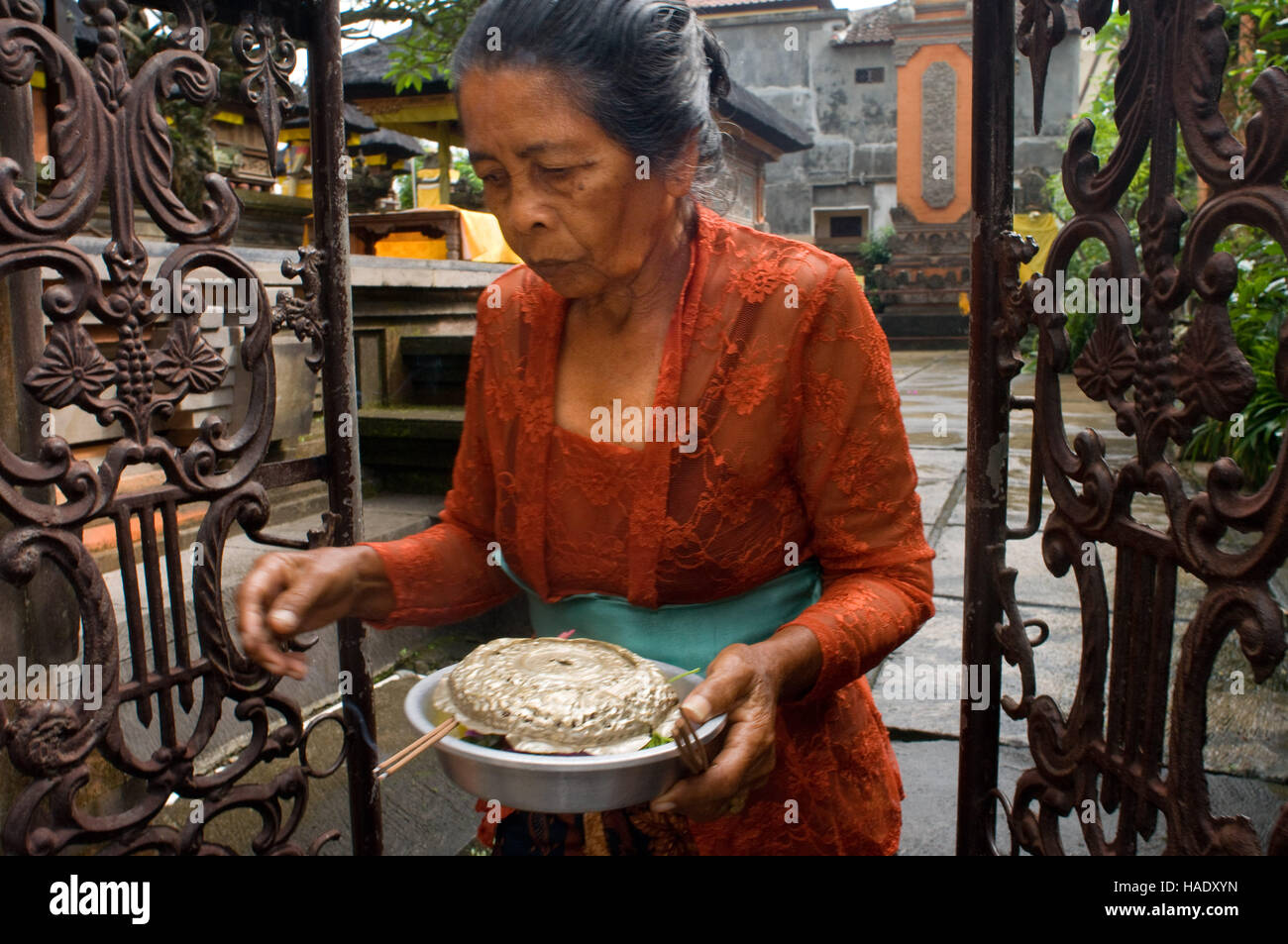 A woman goes into a temple to pray and leave offerings for the celebration of Galungan. Galungan festival, the most important of Bali, symbolizes the Stock Photo