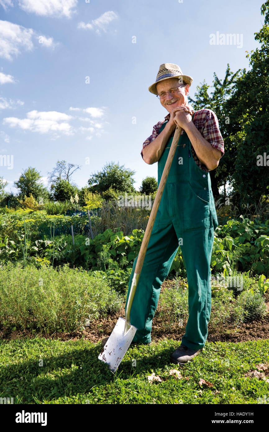 Smiling gardener leaning on his spade Stock Photo