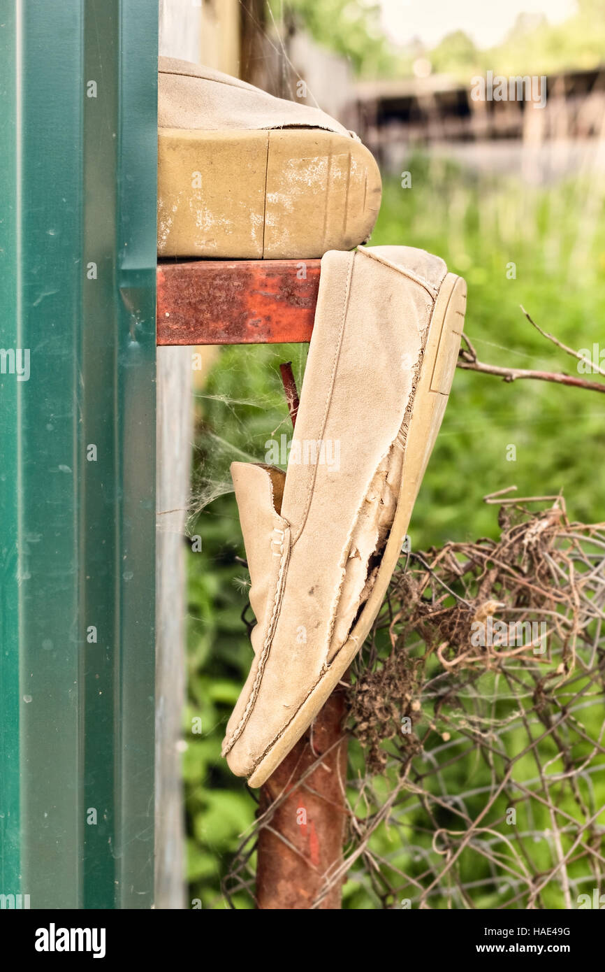 Old ragged shoes on fence at summer day Stock Photo - Alamy
