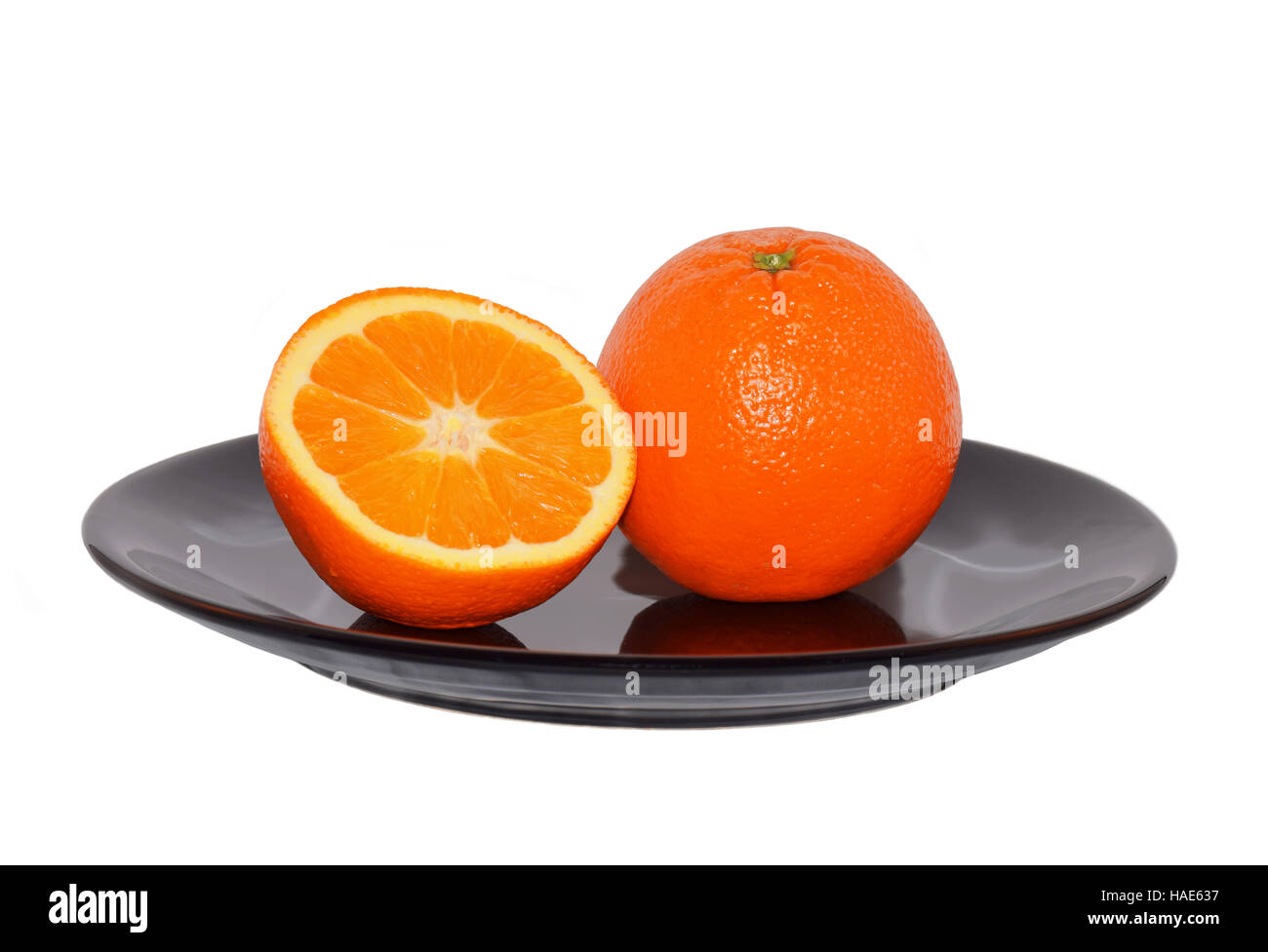 One and half orange on the black plate isolated on white background Stock Photo