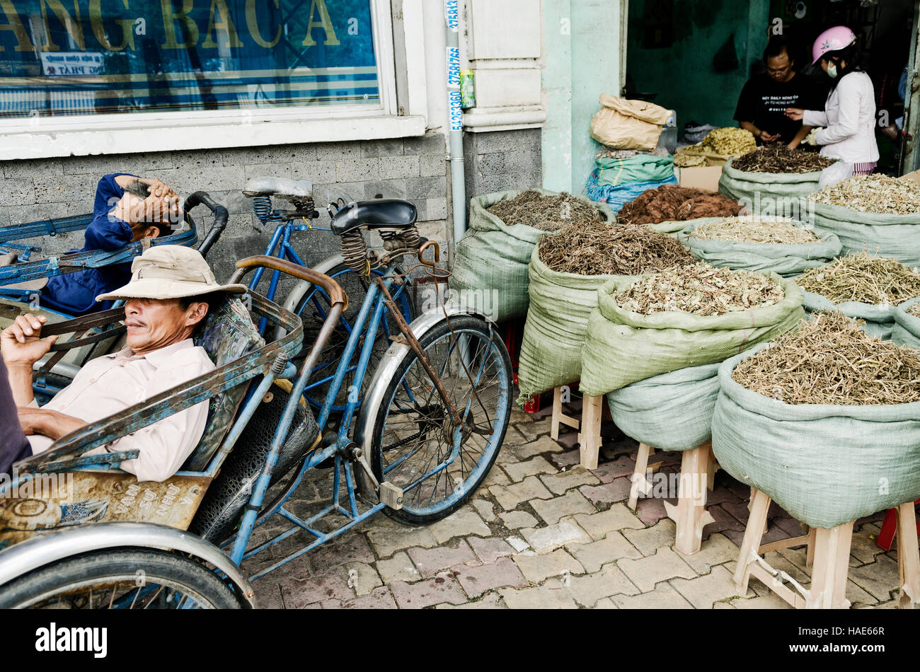 cyclo taxi drivers and herbal shop in saigon ho chi minh city street in vietnam Stock Photo