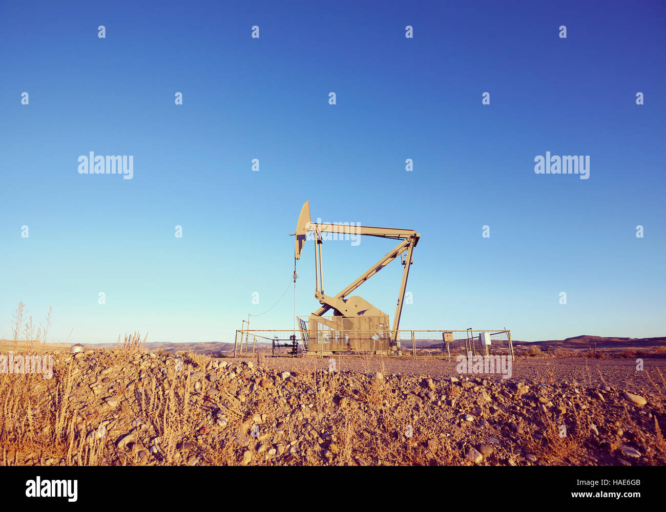 Retro toned picture of an oil pump at sunset. Stock Photo