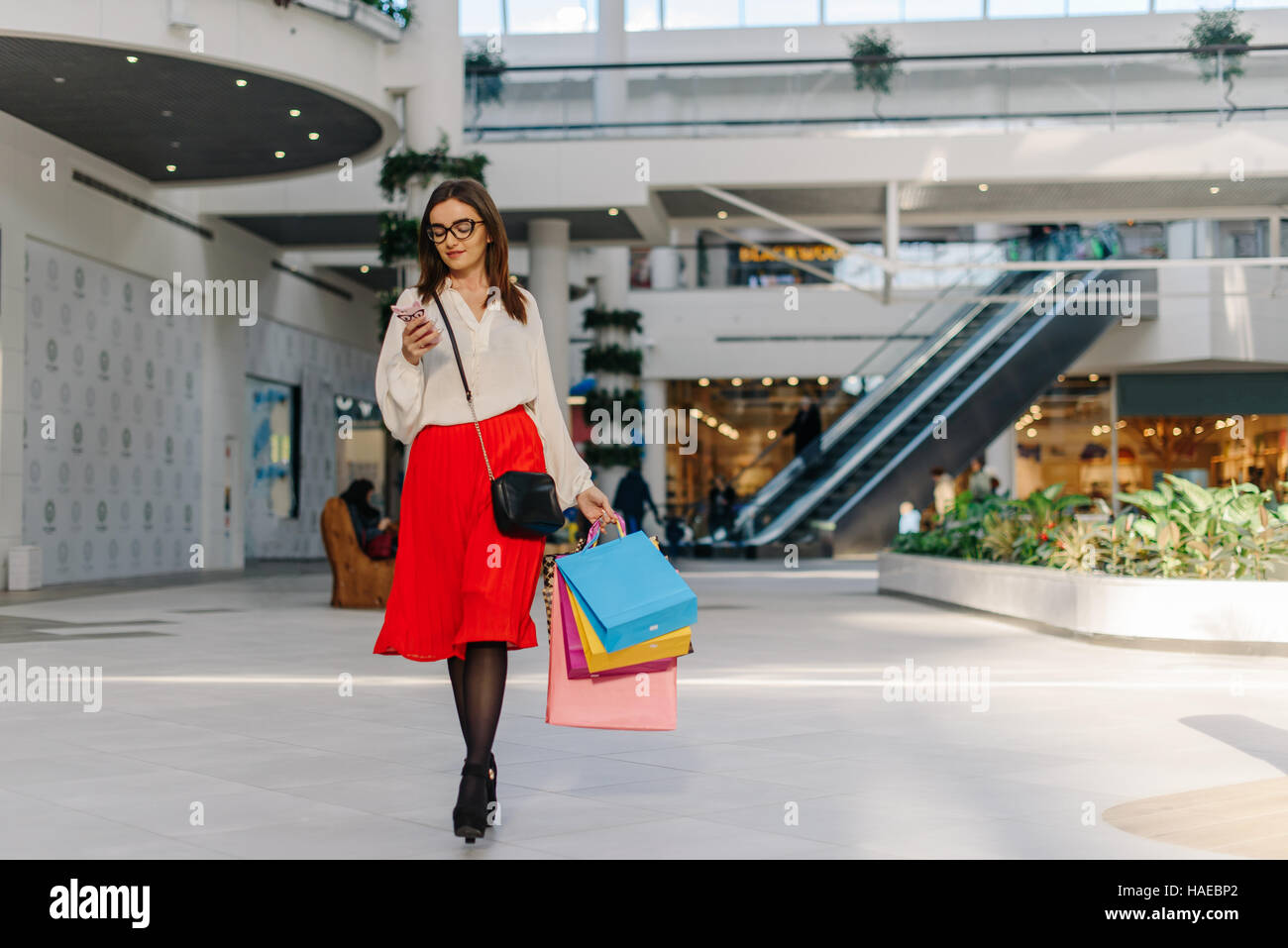 girl in mall after shopping. Attractive woman wearing midi red skirt, white shirt