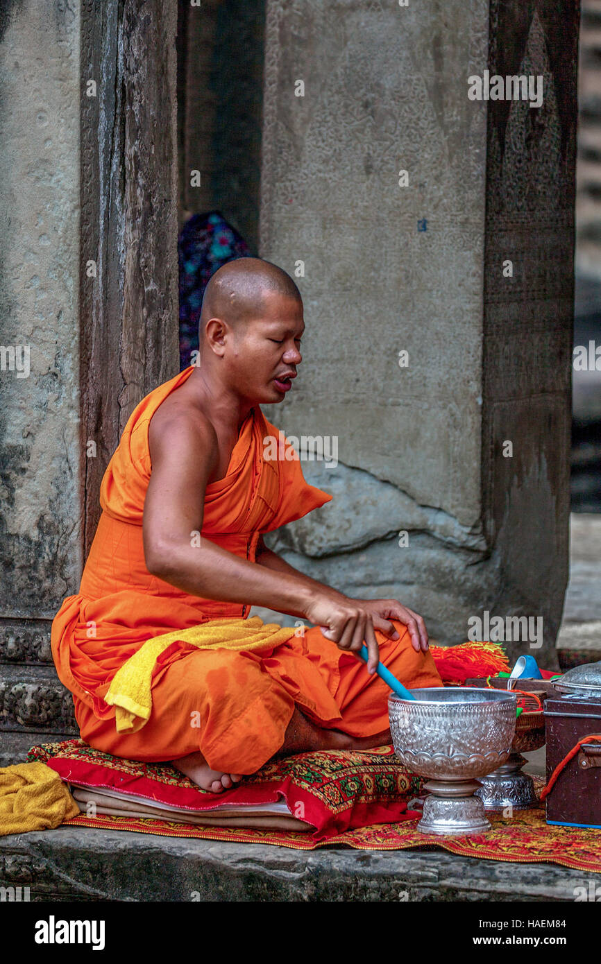 Cambodian monk in orange rove performs rituals at Angkor Wat, Siem Reap, Cambodia. Stock Photo
