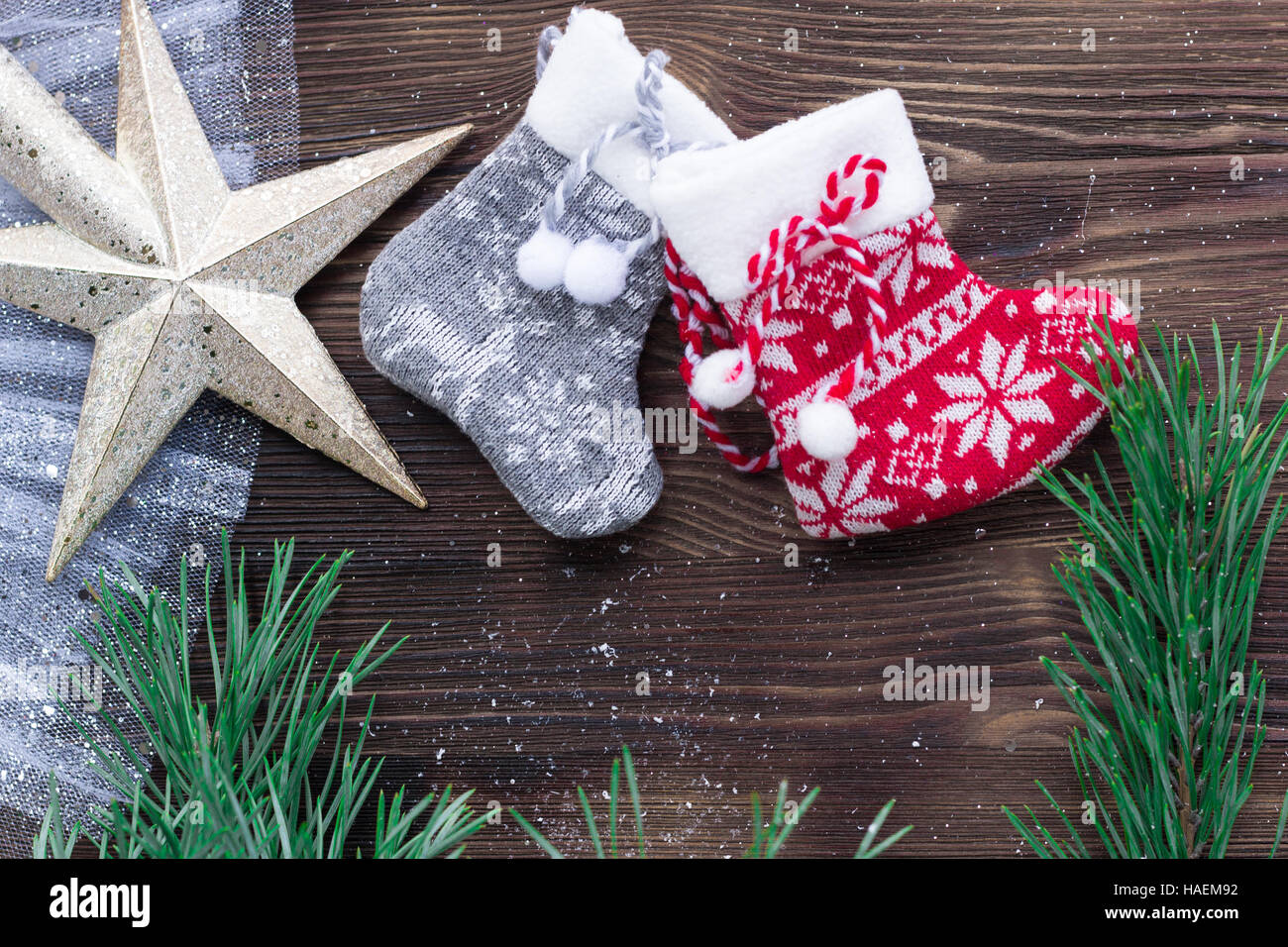 Christmas composition of two knitted socks and xmas tree branches and star ornament on wooden background Stock Photo