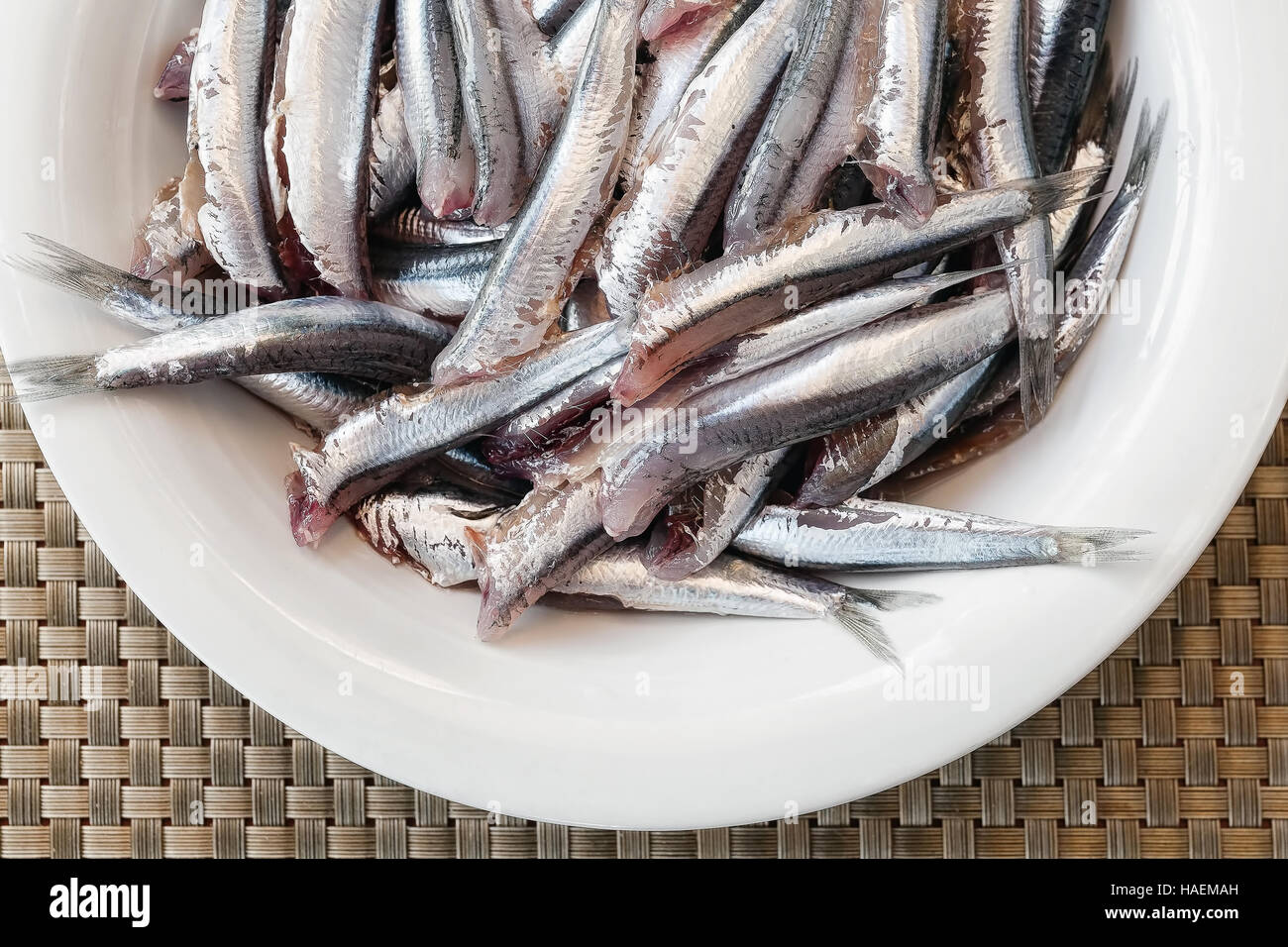 Anchovies headless, clean and ready to be cooked. white plate Stock