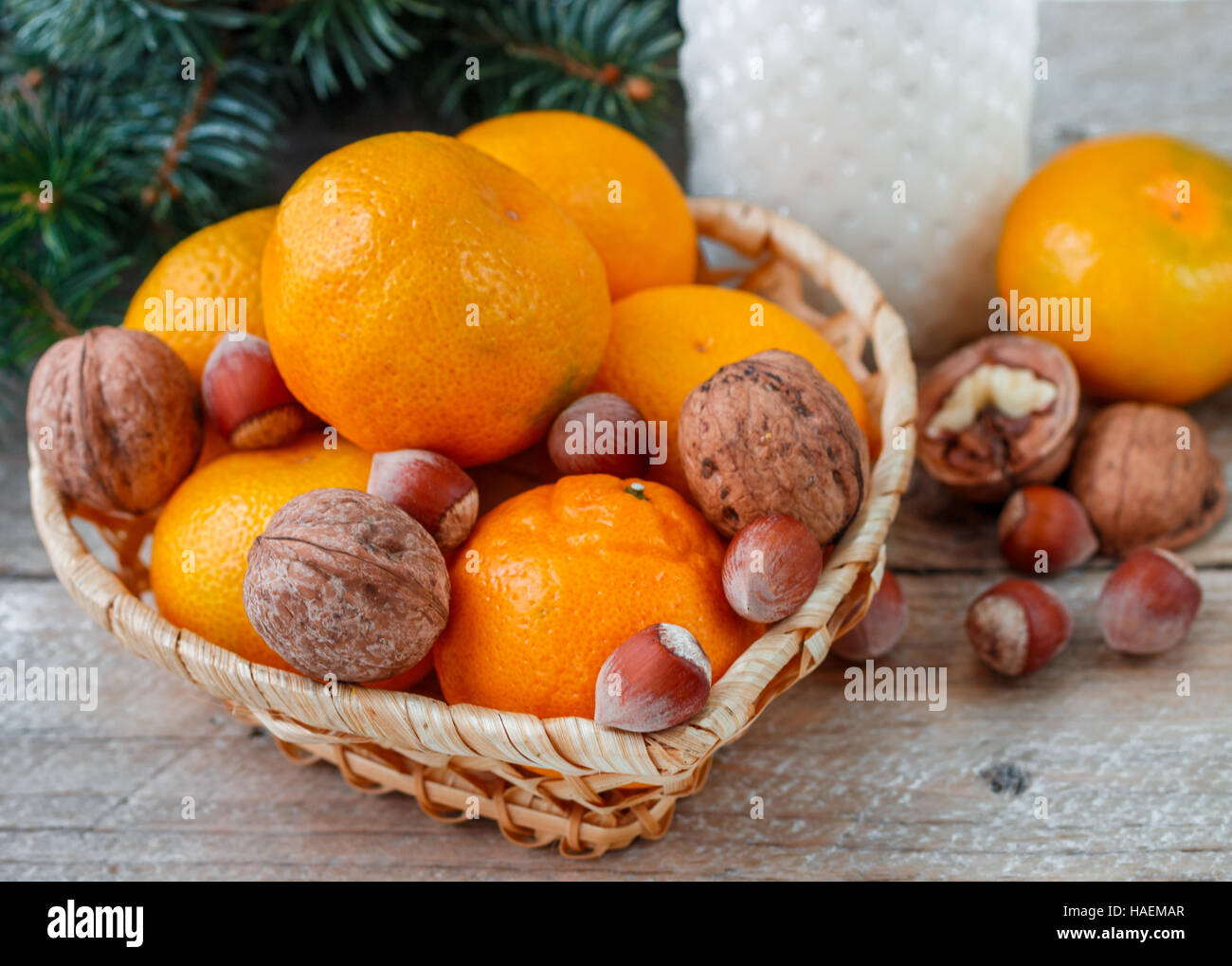 Tangerines and nuts in a wicker basket on the background of fir branches. Christmas. New year. Selective focus Stock Photo