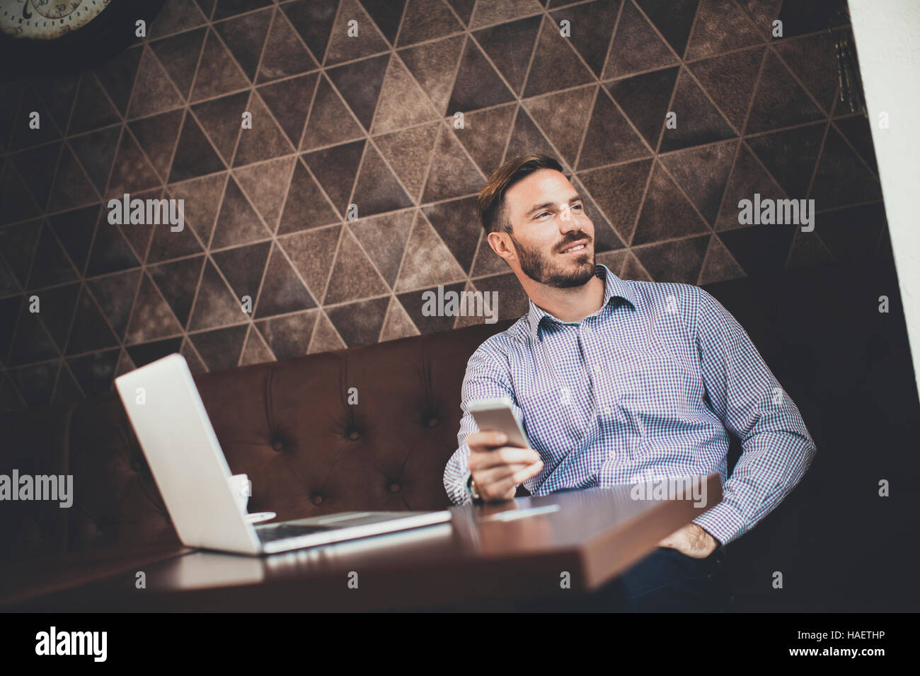 Young man sitting in cafe and using laptop and mobile phone Stock Photo