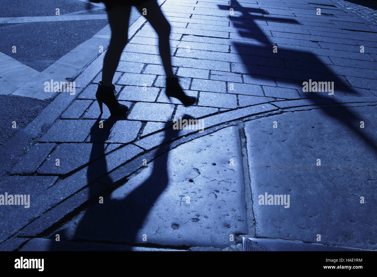 Blue night shadows and silhouette of a woman walking down a New York City sidewalk Stock Photo
