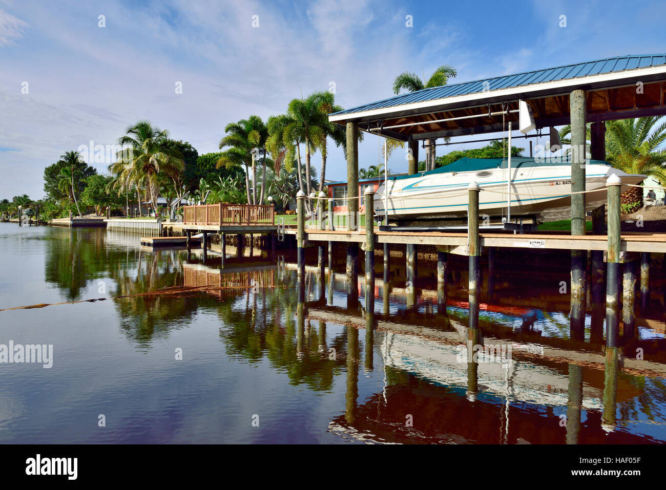 Canal in residential neighborhood with docks and boats at bottom of household gardens, St James City, Florida Stock Photo