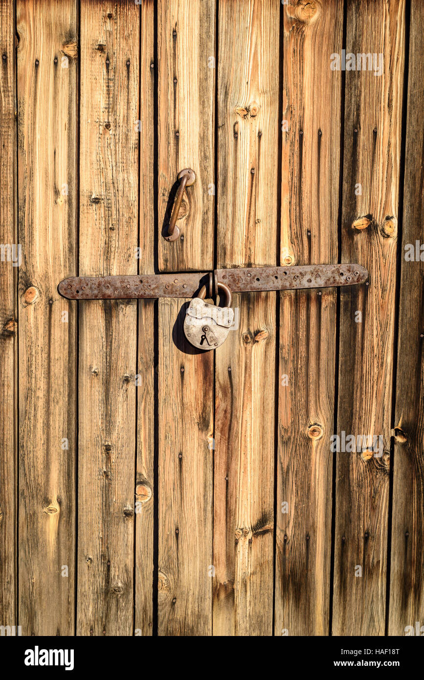 Old vintage metal industrial style hinge on faded textured wood. The wood is brown with grains and patterns due to weathering. Horizontal composition Stock Photo