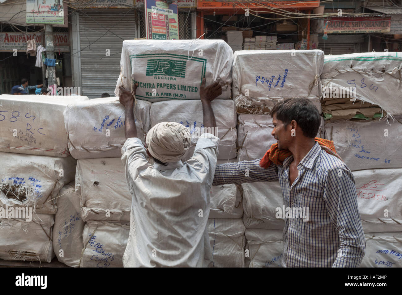 Men loading wrapped goods (unknown) onto a barrow or wagon, Old Delhi, India Stock Photo