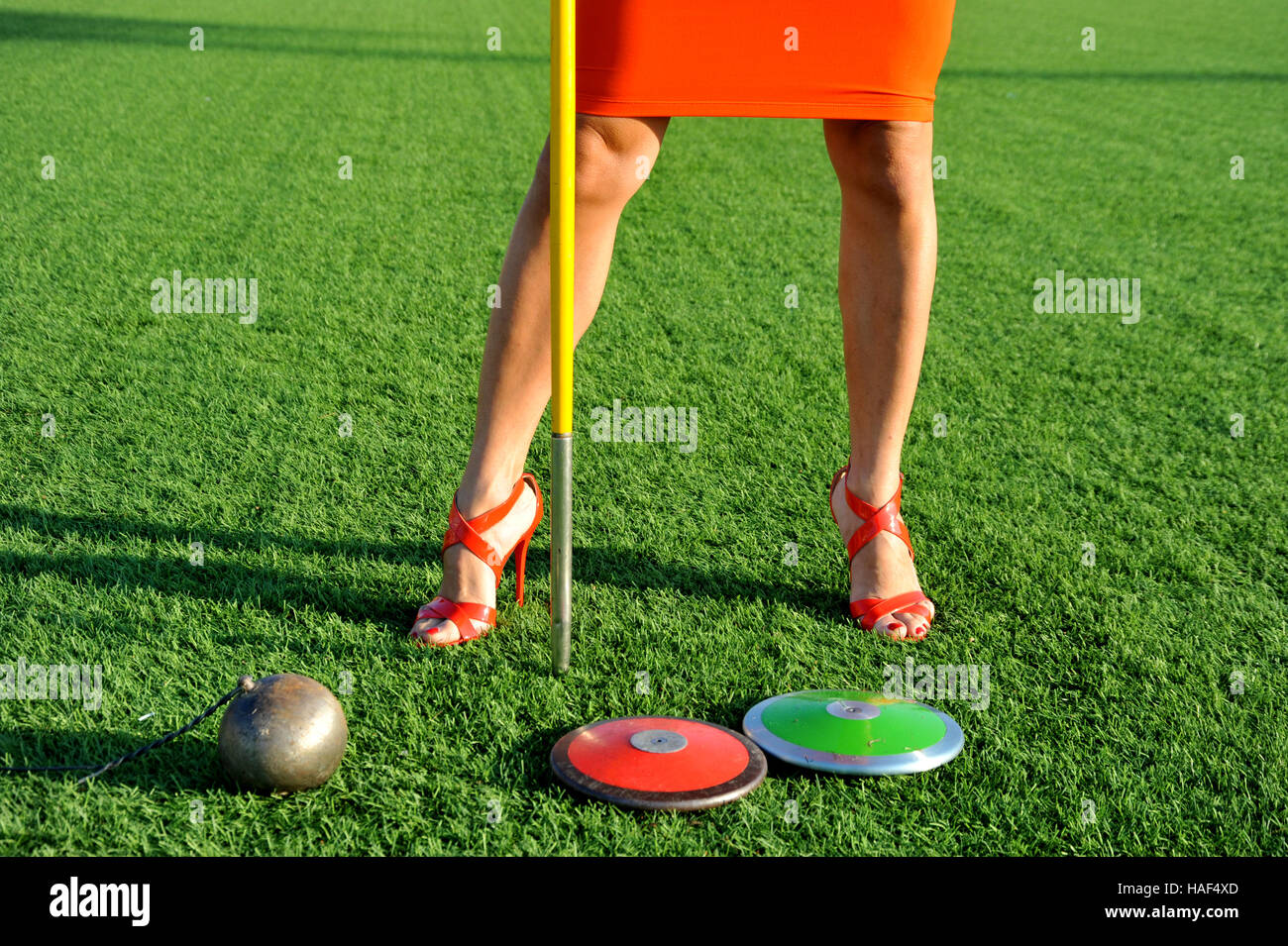 girl with high-heeled shoes and athletic gear, discus, javelin and hammer Stock Photo