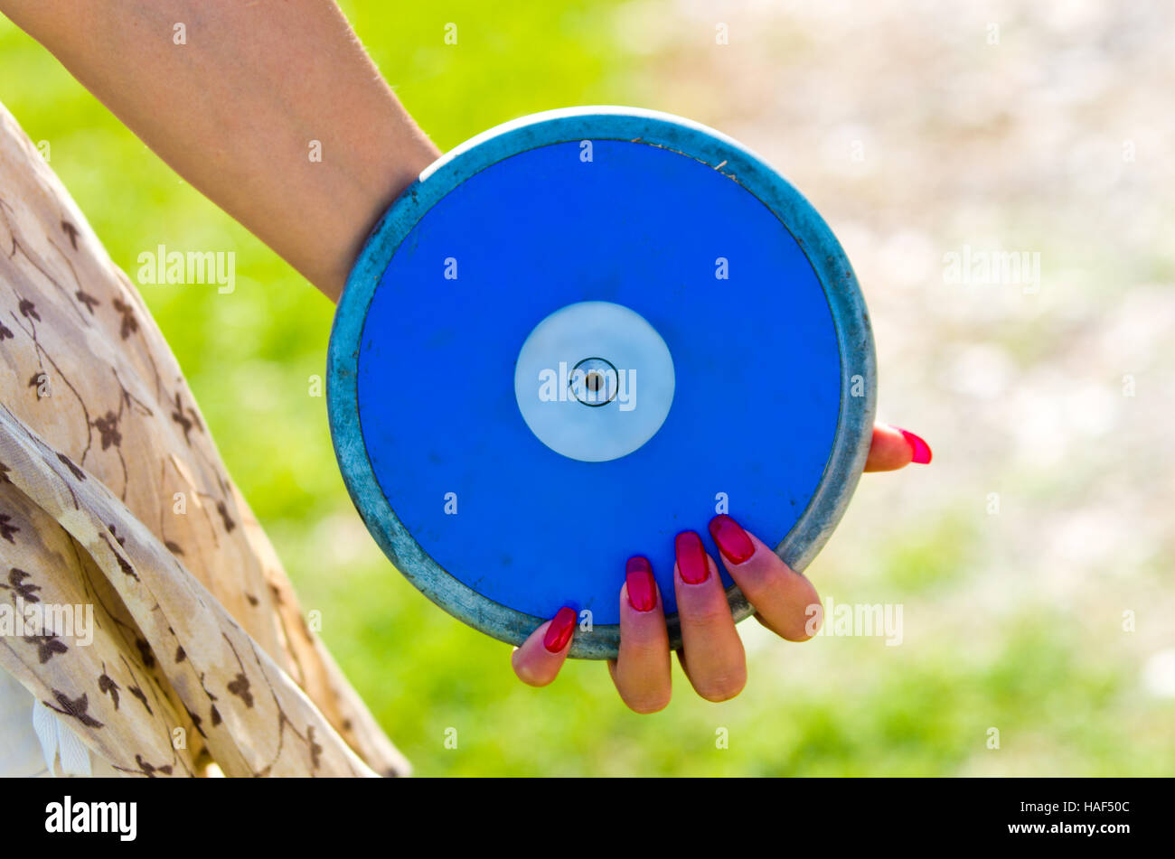 blue disc close to a hand with red fingernails ready to be launched Stock Photo
