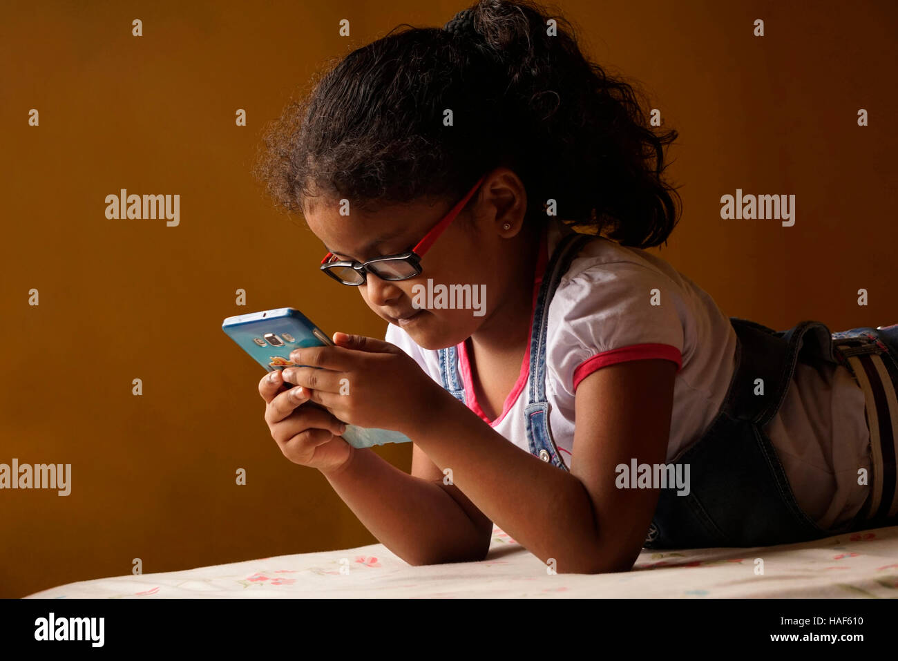 Little girl looking closely at her mobile phone at home, Pune