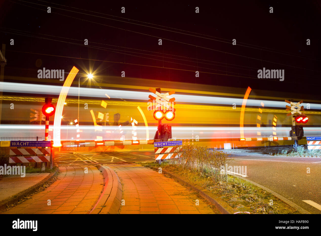 Closing barrier at railway crossing  with speedy passing at night Stock Photo