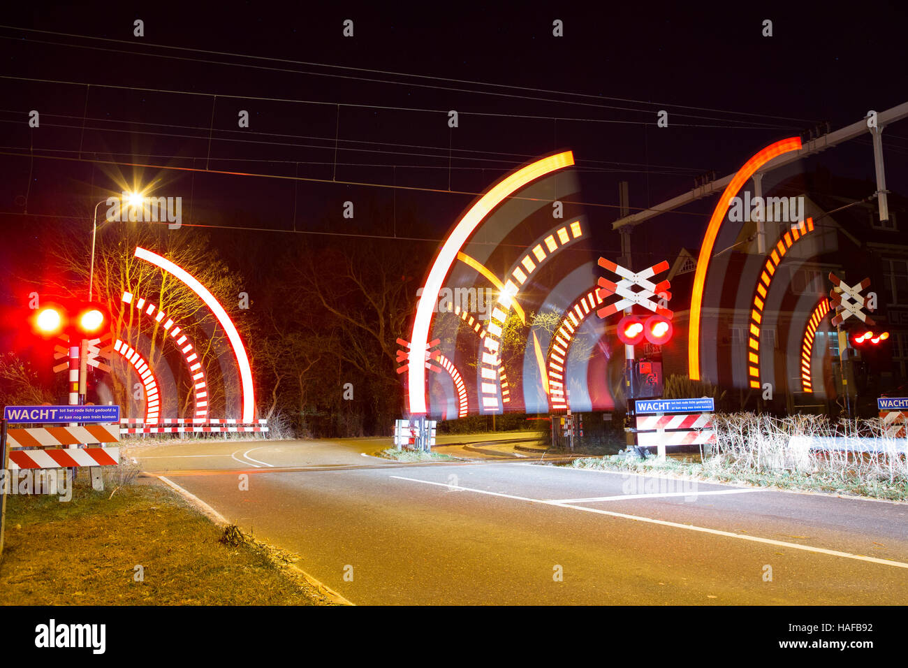 Barrier closing at railway crossing at night Stock Photo