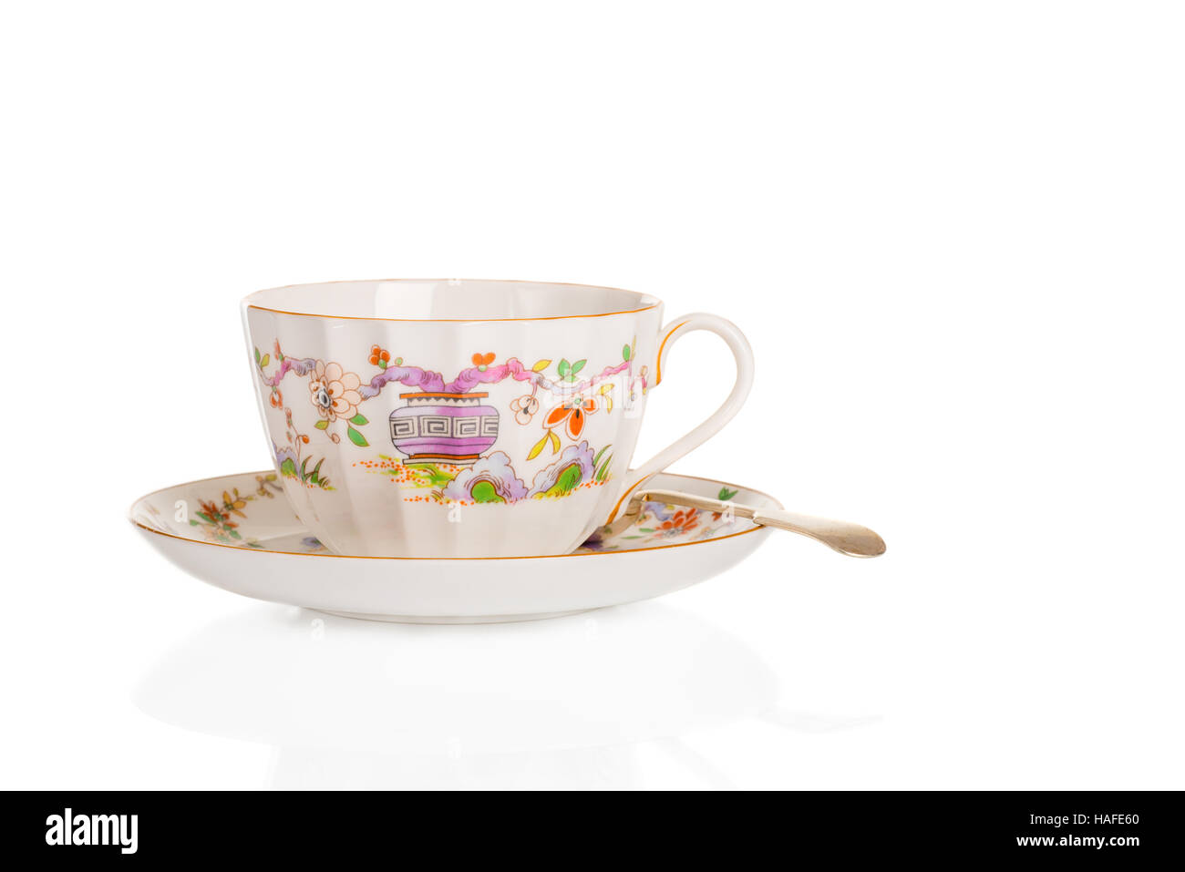 Antique fluted teacup and saucer with spoon on a white background Stock Photo