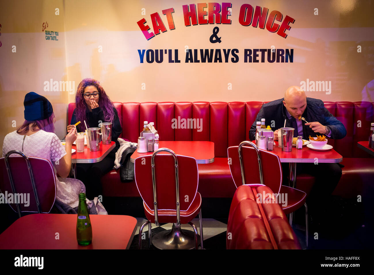 view through window of cafeteria showing customers eating and text advertising benefits of the diner Stock Photo
