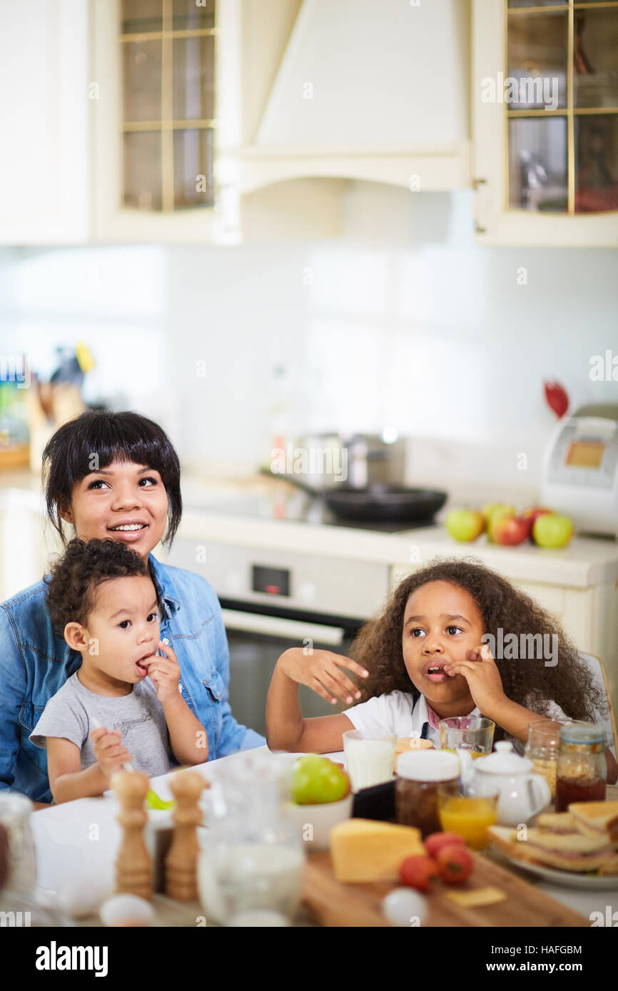 Mixedrace family sitting by table in the kitchen Stock Photo Alamy