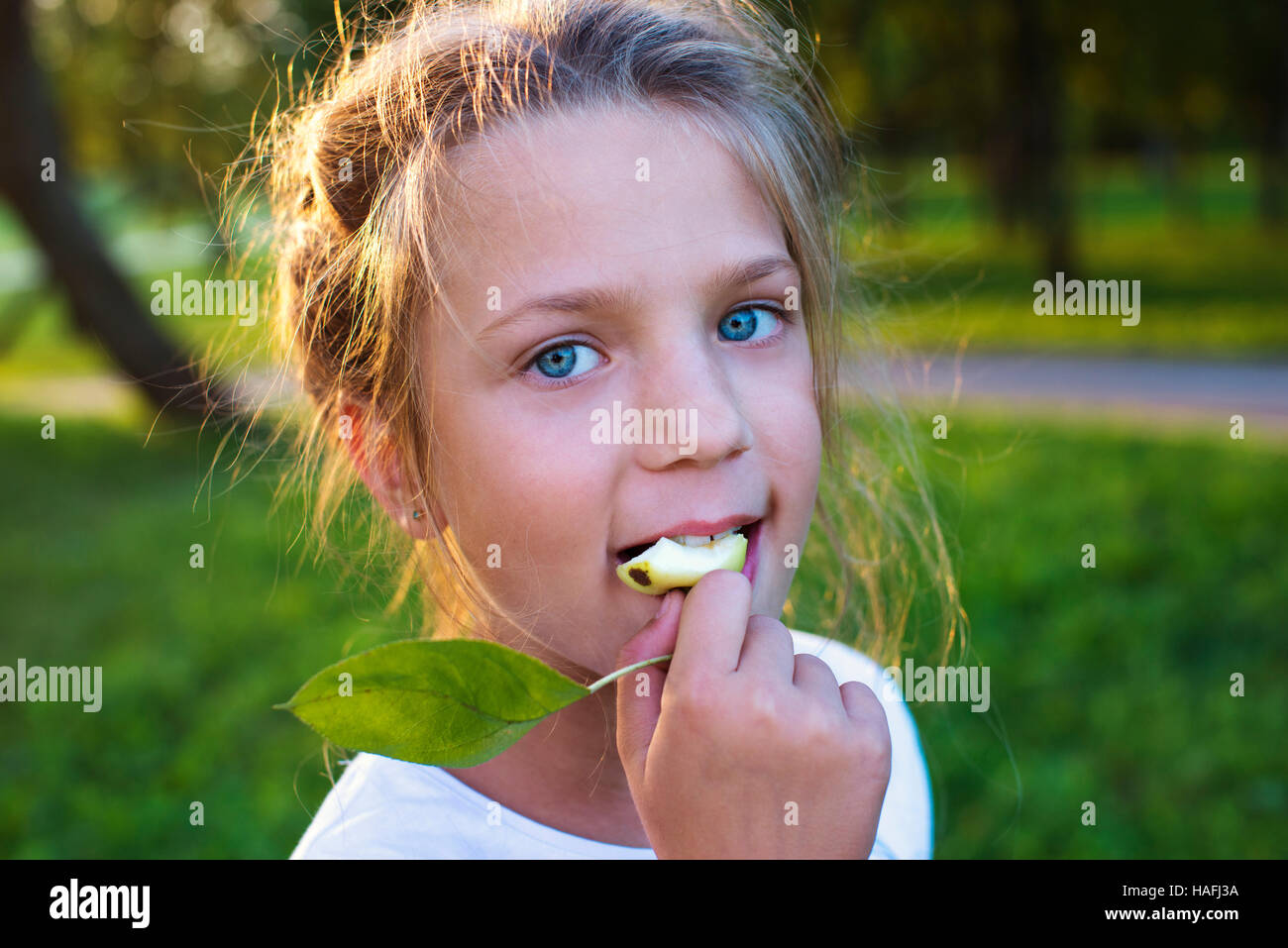 girl eating green apple by summer evening Stock Photo - Alamy