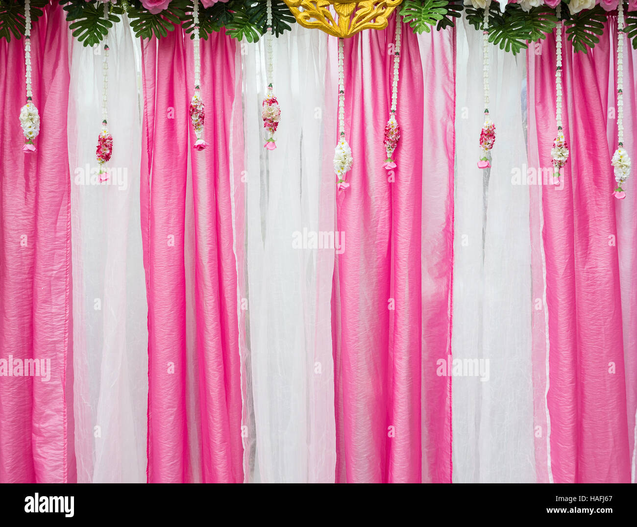 Pink and white fabric backdrop with the fresh floral of the wedding ceremony. Stock Photo