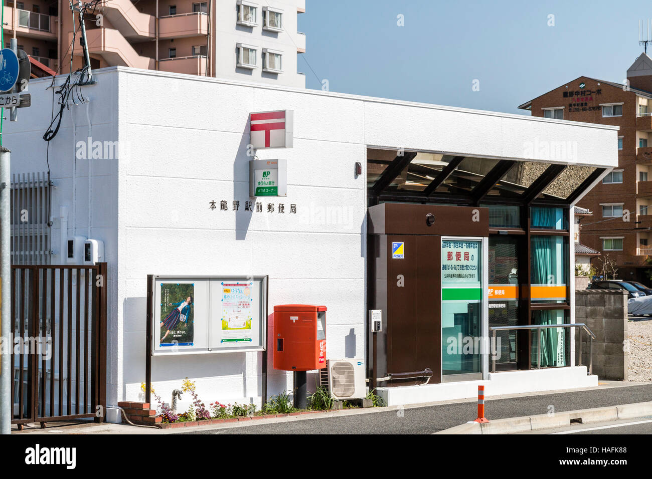 Japan, Tatsuno. Main post office building with post box, and post office sign outside. Exterior. Post office logo sign on side of building. Stock Photo