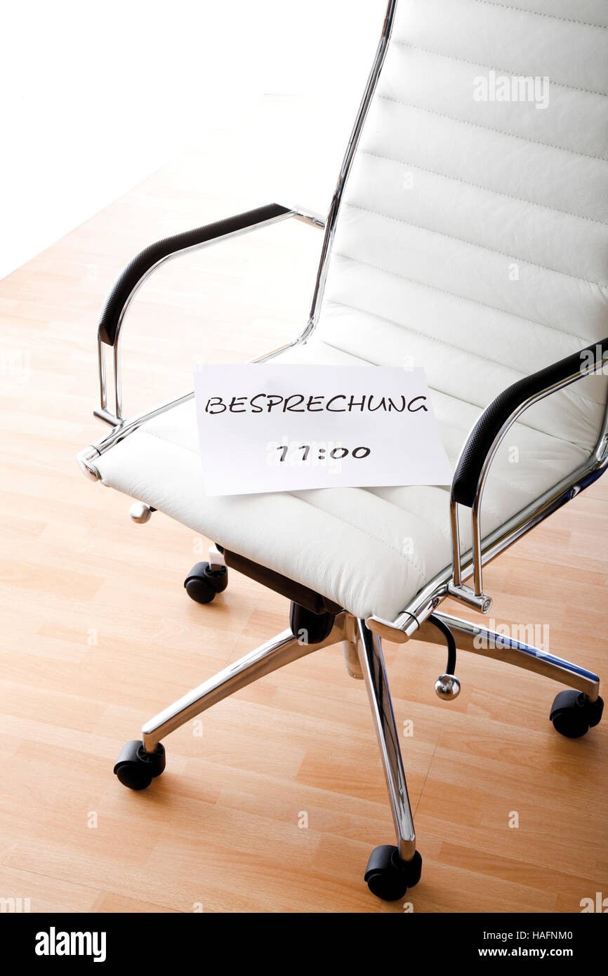 BESPRECHUNG 11 UHR or Conference 11am, sing on an office chair Stock Photo