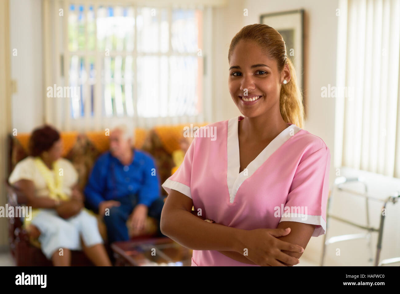 Portrait of girl at work as nurse in medical clinic for seniors. Happy worker smiling at camera in hospice. Stock Photo