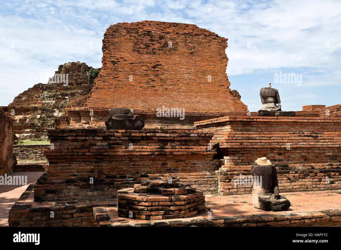 Ruins of the red brick temple of Wat Mahathat, the Temple of the Great Relic, and the remains of some headless Buddha statues, in Ayutthaya, Thailand Stock Photo