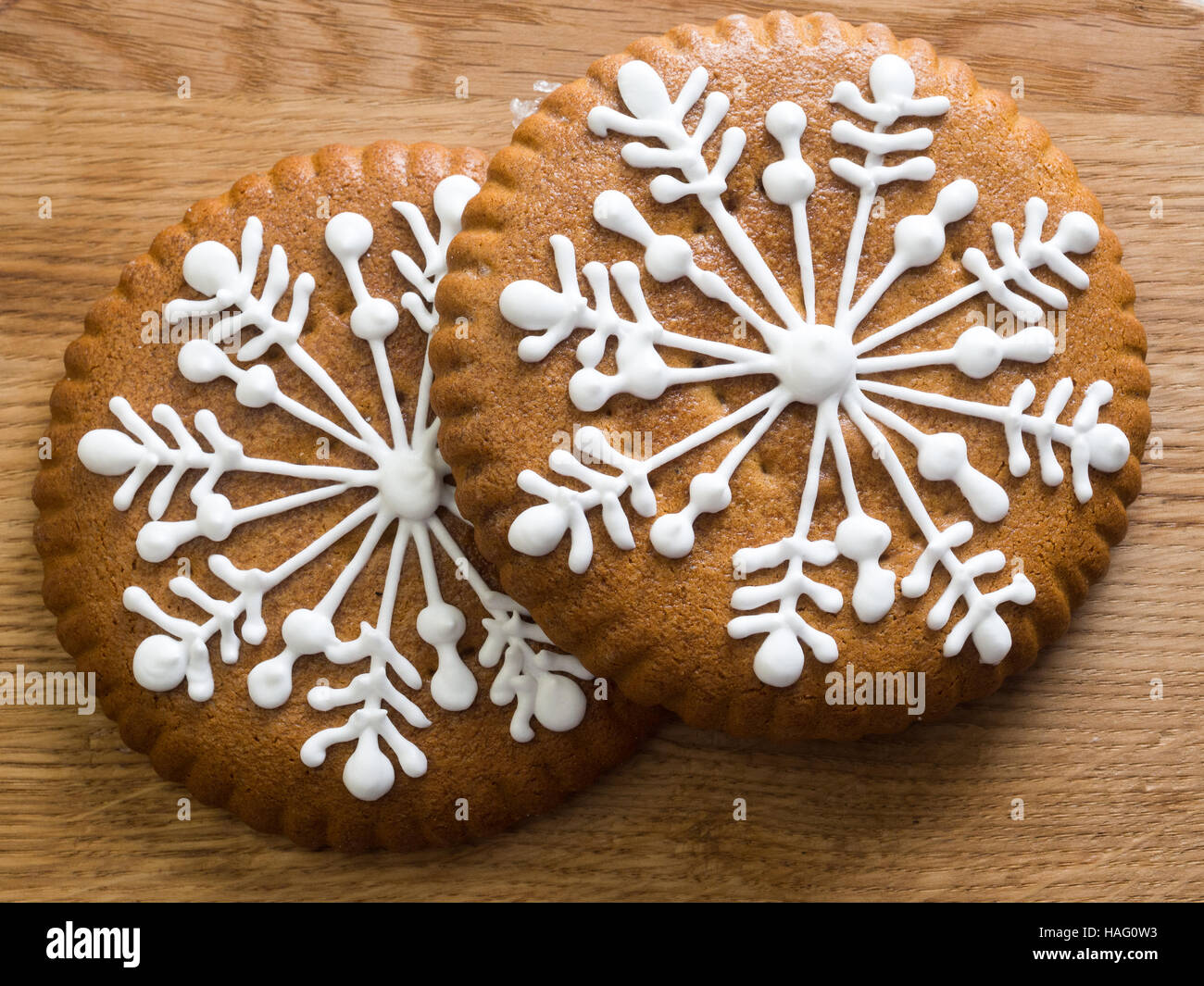 Gingerbread with snowflakes of the glaze. Sweets for Christmas. Two sticks on a wooden board. Stock Photo