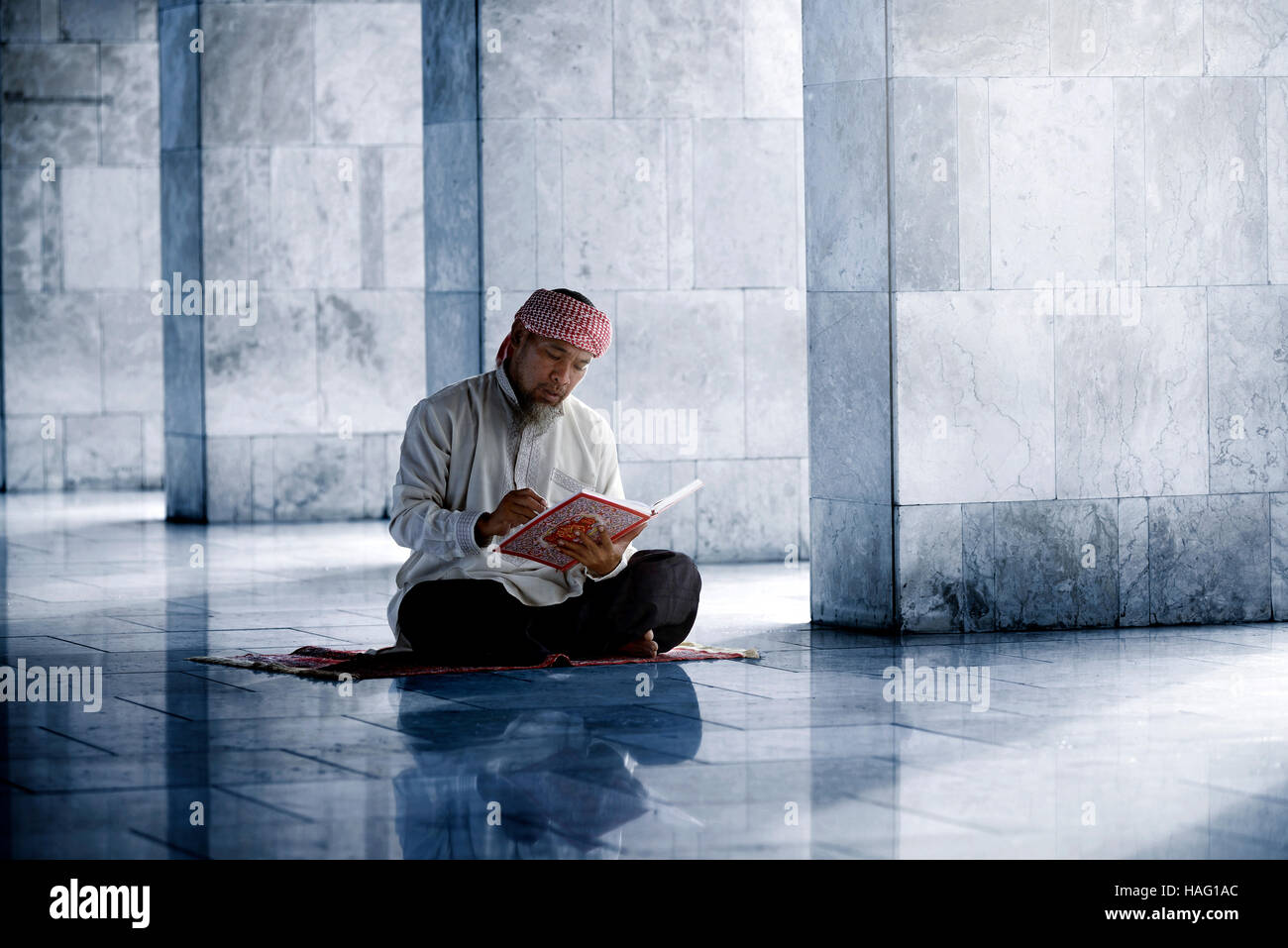 Religious muslim man reading holy koran inside the mosque Stock Photo