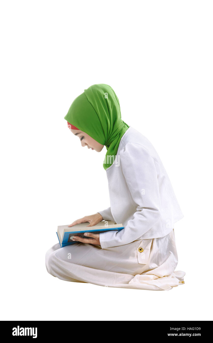Young asian muslim woman reading the koran and she's concentrated reading, isolated background Stock Photo