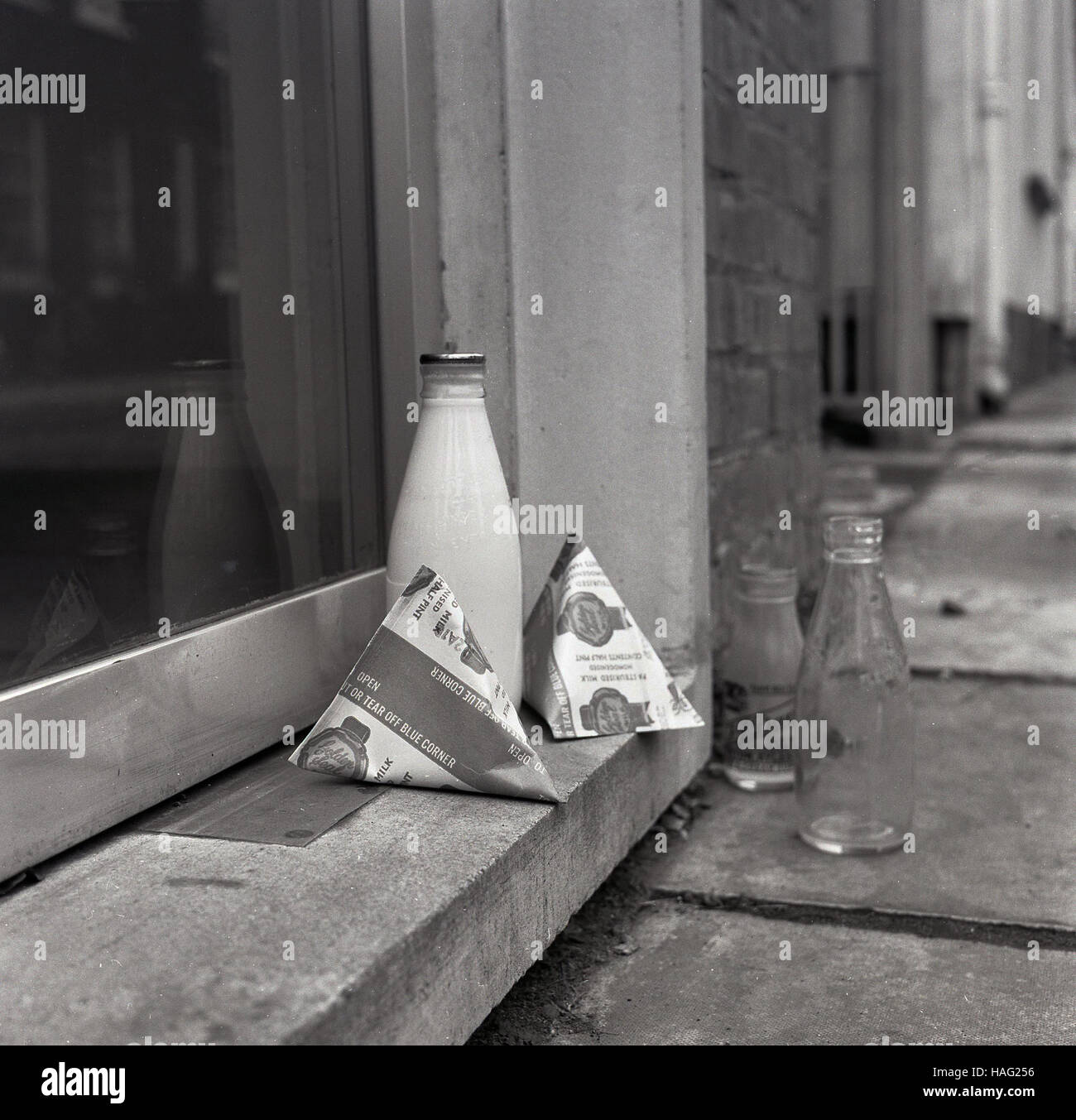 1965, historical, a pint size glass milk bottle and two milk cartons sit on a house doorstep