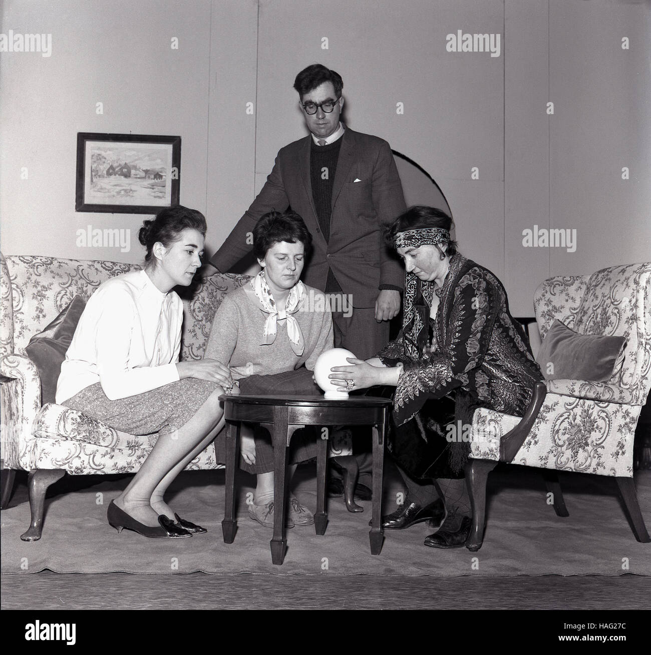 1965, historical, communicating with the spirits sixties style, in the picture we see a female spiritualist medium or pyschic with a light bowl conducting a seance with two ladies. Stock Photo